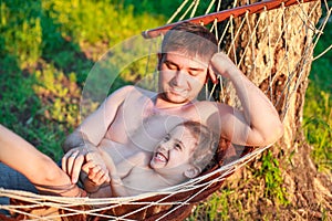 Father dad tickling kid daughter child in hammock