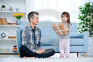 Father and daughter or brother and sister with a gift in the interior of the room. Father`s day holiday concept, Children`s Day