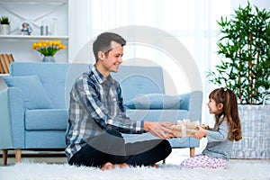 Father and daughter or brother and sister with a gift in the interior of the room. Father`s day holiday concept, Children`s Day