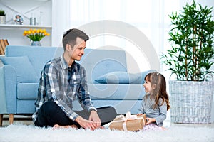 Father and daughter or brother and sister with a gift in the interior of the room. Father`s day holiday concept, Children`s Day