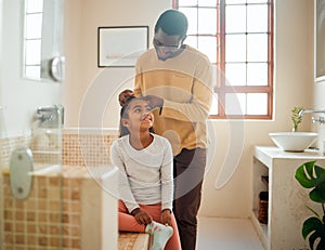 Father, daughter and brushing hair in a home bathroom with love, trust and support. Man teaching child self care, health