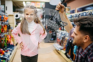 Father and daughter buying muzzle in pet shop