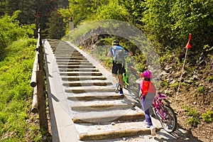 Father and daughter climb the steps with bicycle