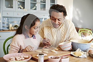 Father And Daughter Decorating Cookies At Home Together