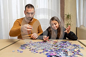 Father and daughter dejected by the difficulty of assembling a puzzle in their living room