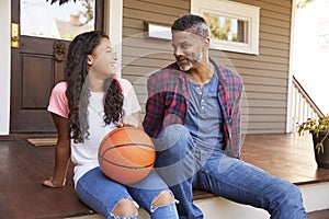 Father And Daughter Discussing Basketball On Porch Of Home