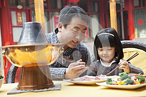 Father and daughter eating Chinese food outside