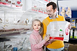 Father and daughter enjoying their purchase of canary bird in pet shop