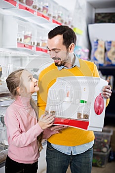 Father and daughter enjoying their purchase of canary bird in pet shop