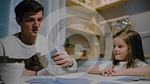 Father and daughter in the evening in the kitchen play board card games.