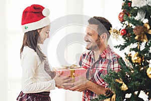 Father and daughter exchanging and opening Christmas presents