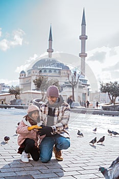 father and daughter feeding the bird together in taksim square photo