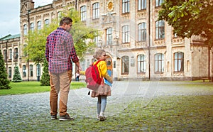 Father and daughter go hand in hand. Back to school. Dad and kid girl of primary school with bag and books. Parent takes