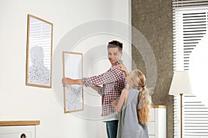 Father and daughter hanging picture on wall