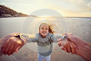 Father and daughter having fun at the beach. Daddy spinning little girl around by the arms by the sea during sunset. Its