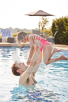 Father And Daughter Having Fun Playing Game In Swimming Pool On Summer Vacation