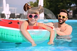 Father and daughter having fun in pool. Family vacation