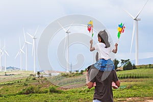 Father and daughter having fun to play together. Asian child girl playing with wind turbine and riding on father`s shoulders