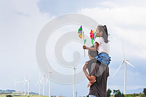 Father and daughter having fun to play together. Asian child girl playing with wind turbine and riding on father`s shoulders