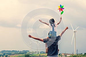 Father and daughter having fun to play together. Asian child girl playing with wind turbine and riding on father`s shoulders