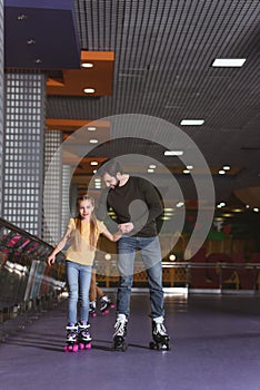 father and daughter holding hands while skating together