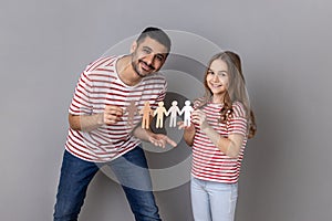 Father and daughter holding paper chain people, symbol of community, unity, people and support.