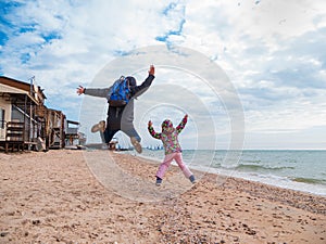 Father and daughter jumping flying in the air on empty beach.Lifestyle photo real people Scenic landscape Vivid blue sea