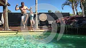 Father and daughter jumping together into swimming pool in slow motion