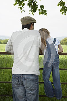 Father With Daughter Looking At Lush Landscape By Fence