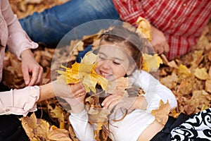 Father and daughter are lying on yellow leaves and having fun in autumn city park. They posing, smiling, playing. Bright yellow