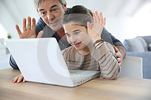 Father and daughter making video call on internet