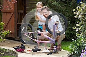 Father And Daughter Mending Bike Together photo