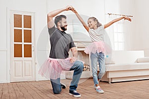 Father and daughter in pink tutu tulle skirts dancing at home