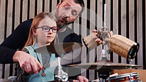 Father and daughter play percussion together.Little girl learning drums with her dad at home.Front view.Percussion class