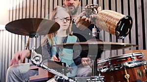 Father and daughter play percussion together.Little girl learning drums with her dad at home.Front view.Percussion class