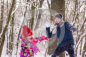 Father and daughter play snowballs in winter forest