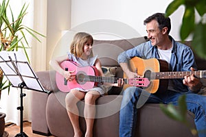 Father daughter playing guitar looking at each other with complicity photo
