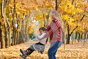 Father and daughter are playing and having fun in autumn city park. They posing, smiling, playing. Bright yellow trees