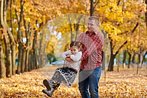 Father and daughter are playing and having fun in autumn city park. They posing, smiling, playing. Bright yellow trees