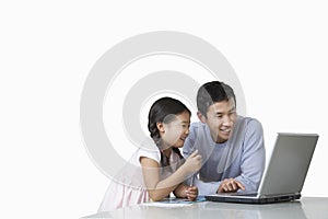 Father and daughter playing with laptop on kitchen counter