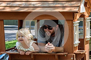 Father and daughter playing in playhouse in backyard