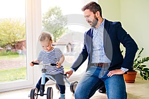 Father and daughter playing together, riding a bike indoors