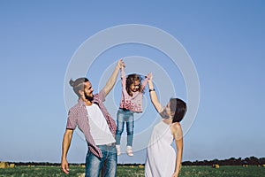 Father, daughter and pregnant mother enjoying life outdoor in field