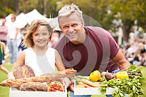 Father And Daughter With Produce From Outdoor Farmers Market