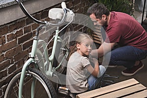 Father and daughter repairing a bicycle at home