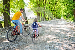 Father and daughter ride bikes in the Park on a Sunny day. Dad teaches the child Cycling