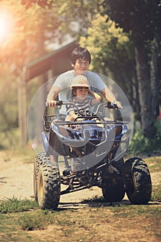 Father and daughter riding on quad atv on dirt field