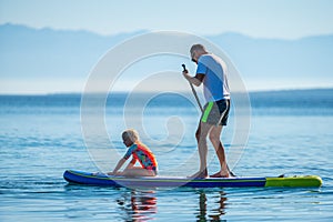 Father and daughter riding SUP stand up paddle on vacation