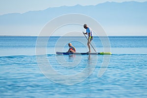Father and daughter riding SUP stand up paddle on vacation
