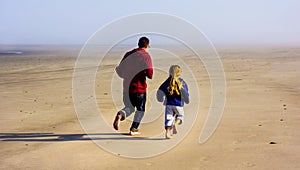 Father and Daughter Run on empty beach sand